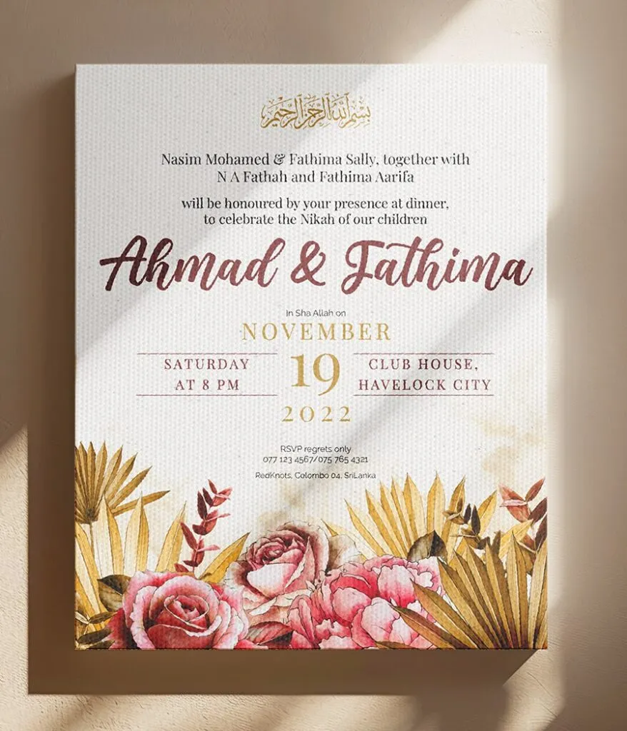 a white and gold invitation with pink flowers and leaves